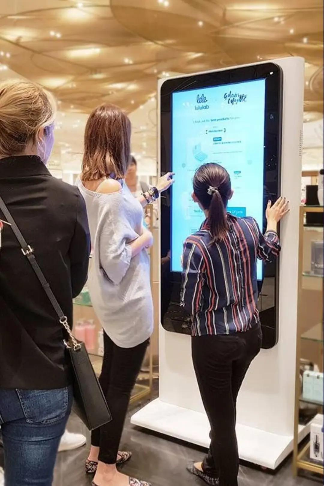Shoppers trying a Lumini skin analysis kiosk in a department store
